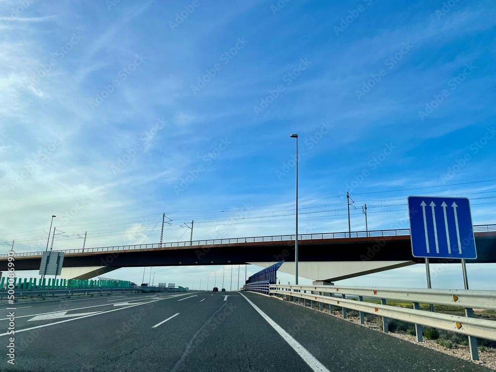 Spanish highway A3 with road sign and railway bridge.