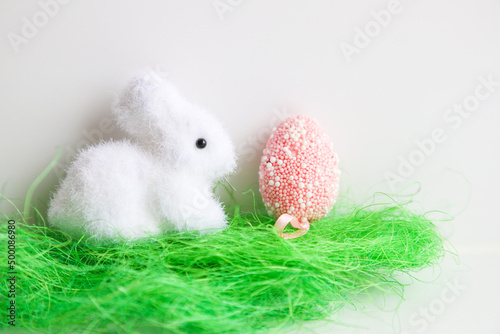 White Easter decorative bunny and pink Easter egg on a white background, close-up. Holiday concept