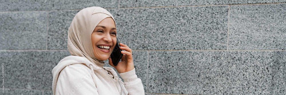 Middle eastern woman in hijab smiling while talking on cellphone Middle eastern woman in hijab smiling while talking on cellphone