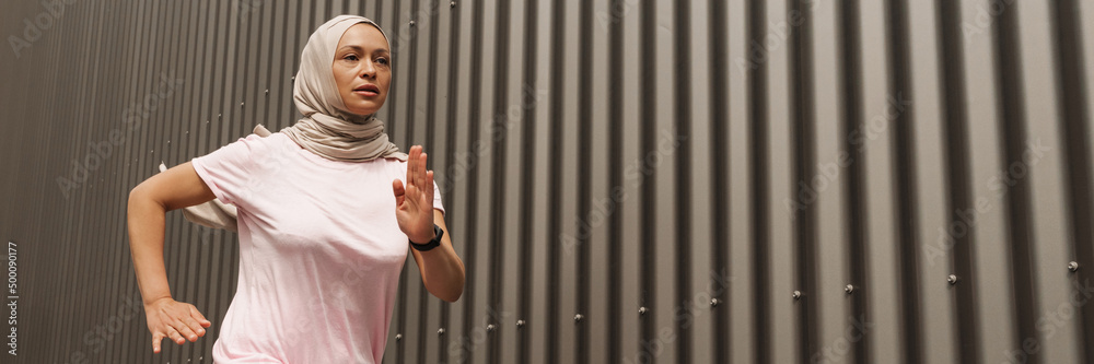 Mid aged muslim woman in hijab exercising outdoors Mid aged muslim woman in hijab exercising outdoors