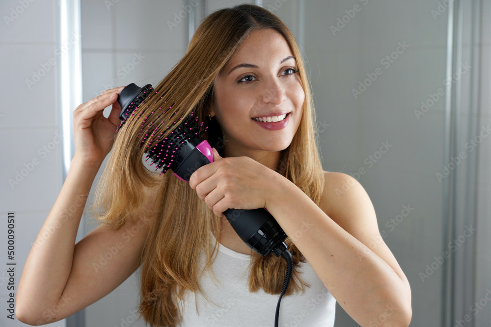 Young woman holds round brush hair dryer to style hair in an easy way at  home Stock Photo | Adobe Stock