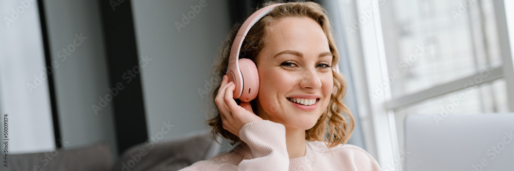 Naklejka premium White woman in headphones using laptop while sitting on floor