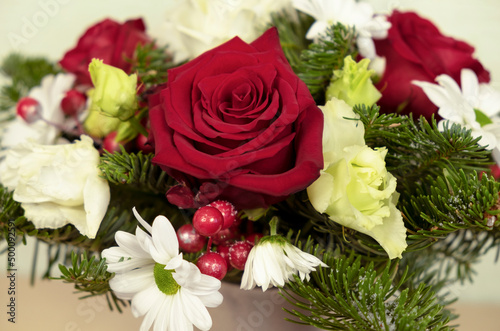 A bouquet of red roses  white chrysanthemums  spruce branches  red berries covered with snow. Winter bouquet