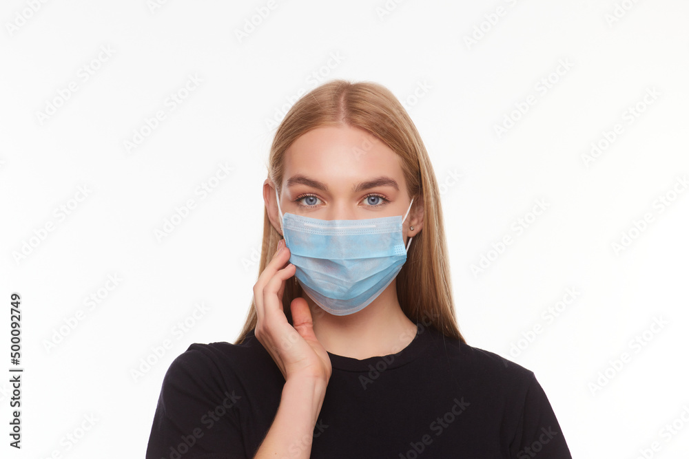 blond young woman wearing medical mask adjusting it with her hands close up blond young woman wearing medical mask adjusting it with her hands close up