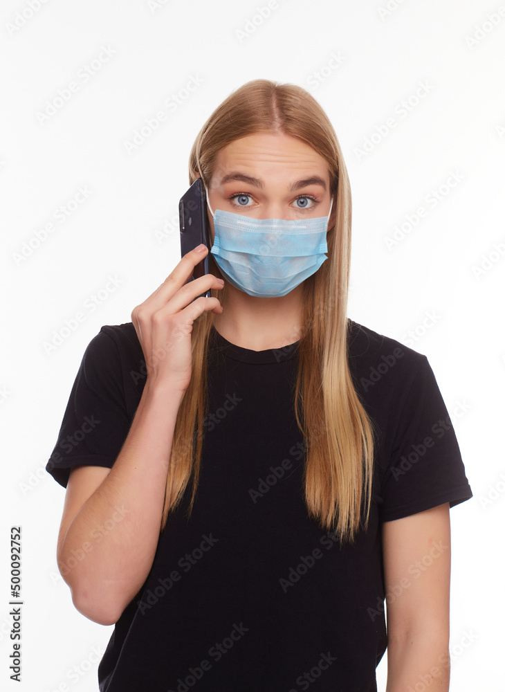 European Girl in a mask uses a telephone. Conceptual photo on the theme of the epidemic. European Girl in a mask uses a telephone. Conceptual photo on the theme of the epidemic.