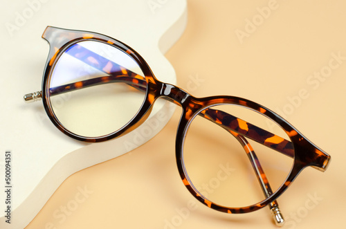 Stylish women's glasses of leopard color on a beige background. Women's accessories. Glasses for vision.