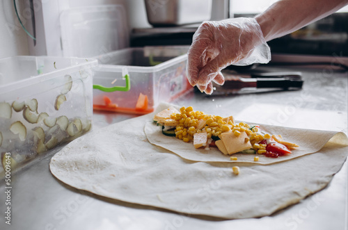 Men's hands wrapping traditional shawarma wrap with chicken and vegetables photo