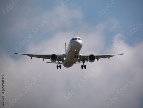Airbus a320 preparing for a landing at Barcelona airport on a sunny day with clouds.