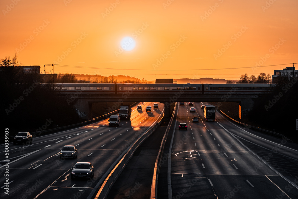 highway at sunset with a bridge and crossing train with medium traffic