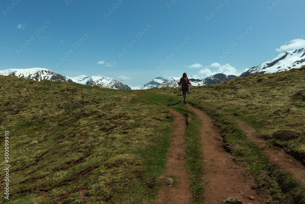 Woman trekking in the Pyrenees approaching the snowy mountains, between Spain and France. near Candanchu