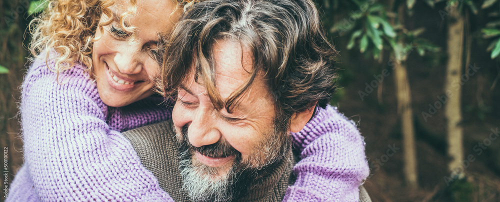 Close up portrait of joyful caucasian couple hugging and loving with forest nature in background. Man and woman smiling and having fun together in outdoor leisure activity. Banner header image Close up portrait of joyful caucasian couple hugging and loving with forest nature in background. Man and woman smiling and having fun together in outdoor leisure activity. Banner header image