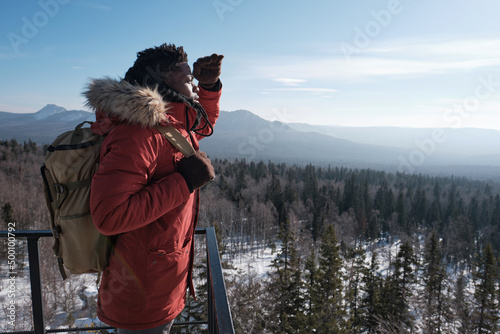 Fotografie, Obraz Young African American traveler wearing backpack standing at observation deck on