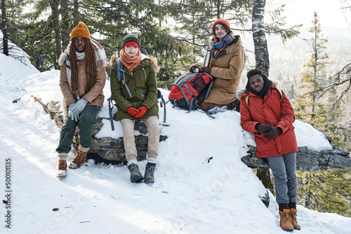 Group of active young African American and Caucasian men and women spending time together in mountains on winter day