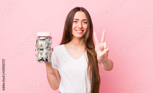 hispanic pretty woman smiling and looking friendly, showing number two. savings concept photo