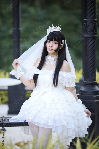 Beautiful young woman with white lolita dress with european garden Japanese fashion