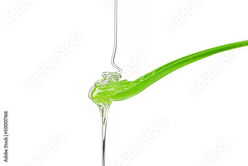 Tablou pe pânză Syrup of glucose pouring, running down green spoon on a white background
