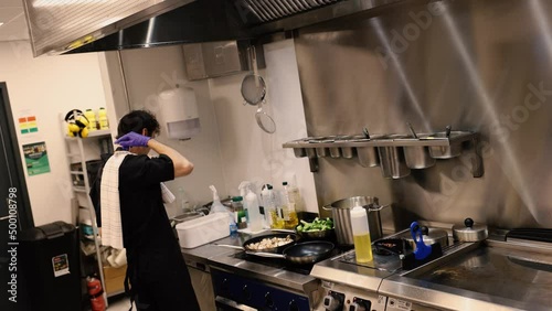 Professional chef in the kitchen of a restaurant. A male chef in a black uniform is working in the kitchen. Slow motion 4K