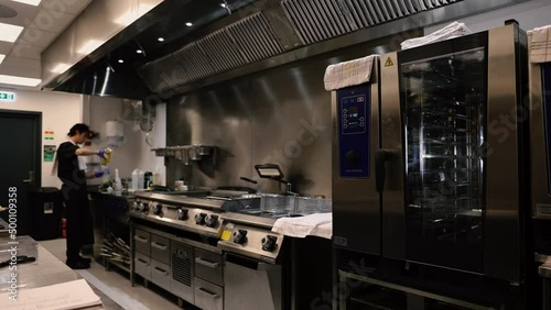 Professional chef in the kitchen of a restaurant. A male chef in a black uniform is working in the kitchen. Slow motion 4K