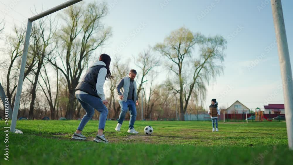 Family football. Happy family playing with a ball on meadow. Parents playing football on a green playground in summer day. Sport and Family. Family football. Happy family playing with a ball on meadow. Parents playing football on a green playground in summer day. Sport and Family.