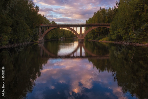 Fototapeta Naklejka Na Ścianę i Meble -  old railway Finnish arch bridge on the Janisjoki river in Karelia at sunset