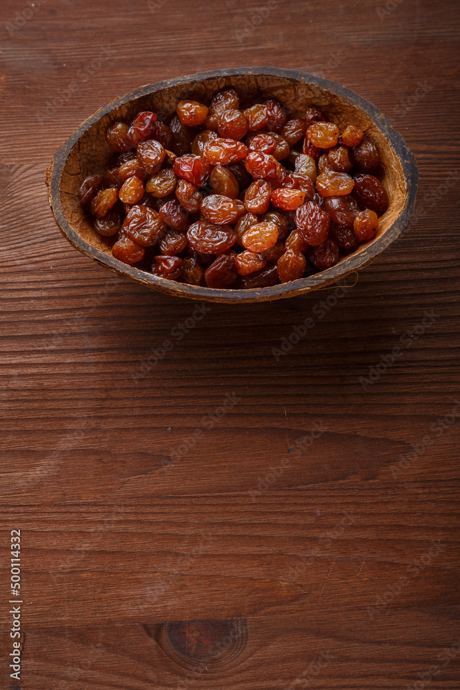 Raisins in a bowl of coconut shell on a wooden table.copy space Raisins in a bowl of coconut shell on a wooden table.copy space