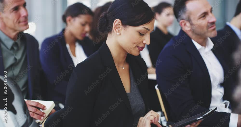Recording important notes on her device. 4k video footage of a young businesswoman using a digital tablet while sitting in a conference.