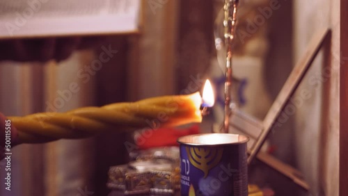 The hand of a Jewish woman lights the Avdala candle after Shabbat. Medium plan photo