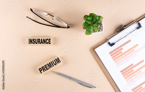 INSURANCE PREMIUM text on wooden block with chart and glasses, business concept