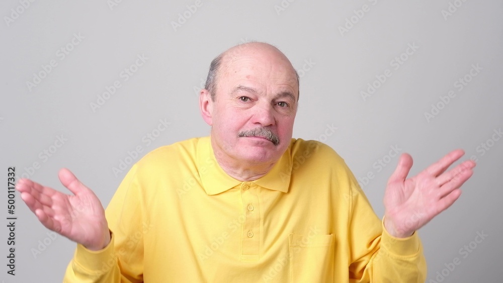 Senior man standing gesturing with hands like he does not know what to choose. Senior man standing gesturing with hands like he does not know what to choose.