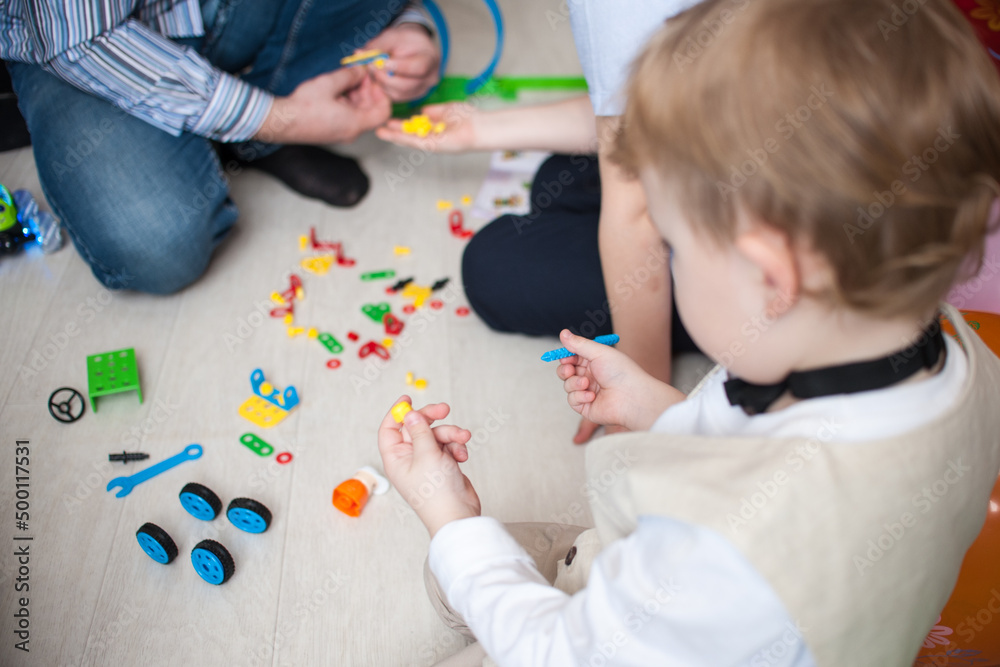 Boy and dad assemble constructor sitting on the floor