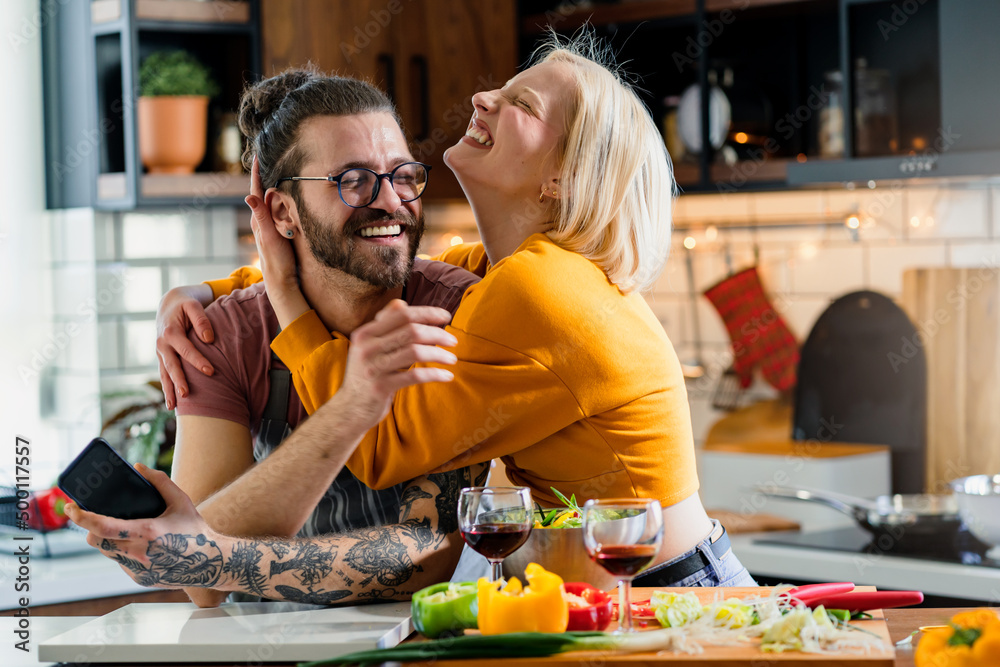 Young cheerful love couple preparing a healthy vegan lunch at home and have fun