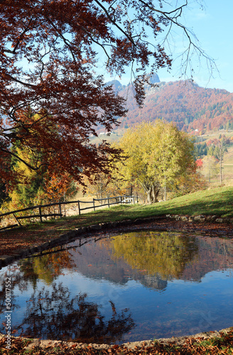 mountains and woods with the autumn colors of the trees and the reflection on the alpine lake