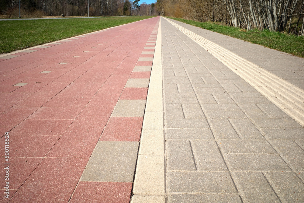Pedestrian and bike paths converge on the horizon. Perspective. A special relief strip on the pavement for blind people.