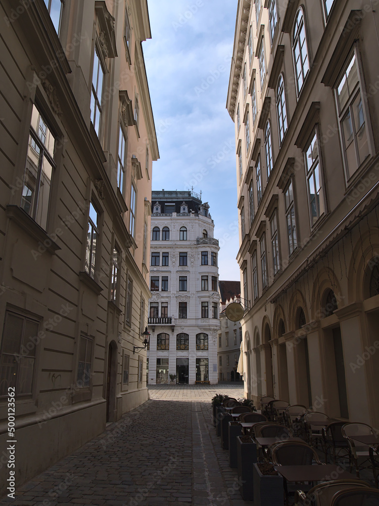Beautiful view of empty narrow alley in the historic downtown of Vienna, Austria on sunny day with shadow between old buildings with ornate facades.