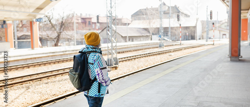Wallpaper Mural Old happy woman with backpack in yellow hat waiting train on station platform on urban background. Railroad transport concept Torontodigital.ca
