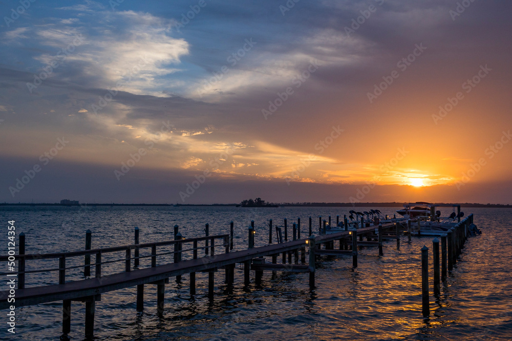 Colorful sunset over a pier with dramatic clouds.