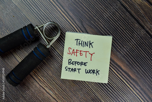 Think Safety Before Start Work write on sticky notes isolated on Wooden Table.