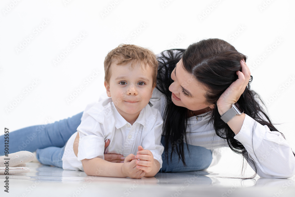 Happy smiling woman and boy lying on floor, white background. Hugging, talking caring parenthood. Autism spectrum. Close Happy smiling woman and boy lying on floor, white background. Hugging, talking caring parenthood. Autism spectrum. Close