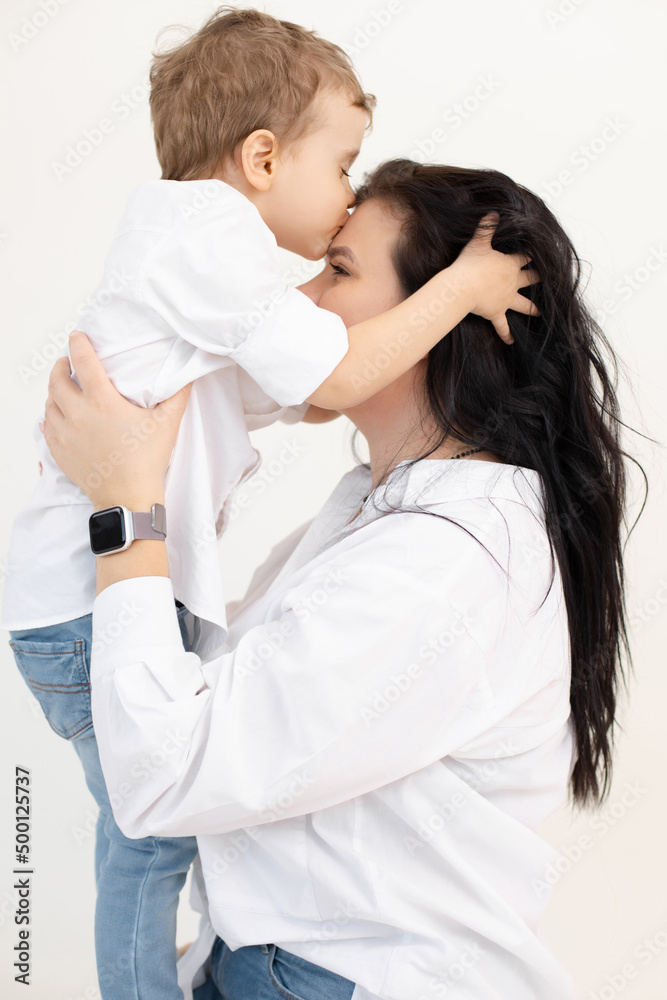 Vertical portrait of single mother, dark haired woman with little boy, her son, embracing together, kissing each other Vertical portrait of single mother, dark haired woman with little boy, her son, embracing together, kissing each other