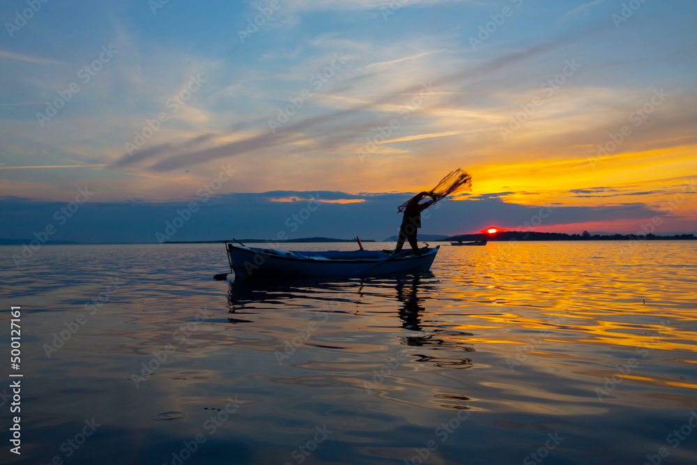 Fishing town and fishermen casting nets in the sea, sunset time Stock Photo