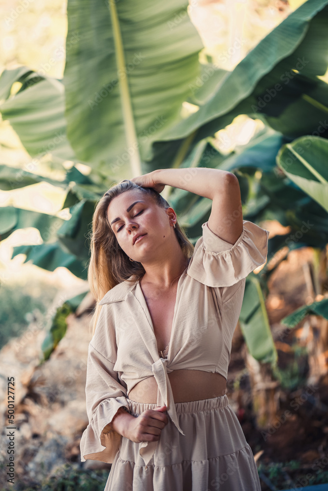 A woman stands near green banana leaves on the island. Tropical trees. Selective focus A woman stands near green banana leaves on the island. Tropical trees. Selective focus