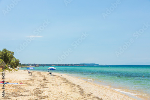 Beautiful seascape view. People on sand beach on turquoise water and blue sky background. Greece.