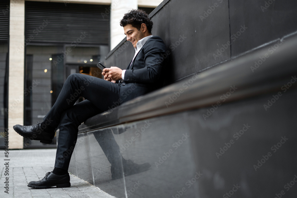 A male business manager in a formal suit uses the phone and goes to work in the office