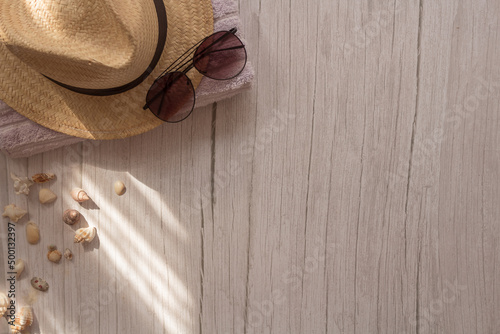 sombrero, lentes de sol y toalla en mesa con conchas de mar y rayos de sol