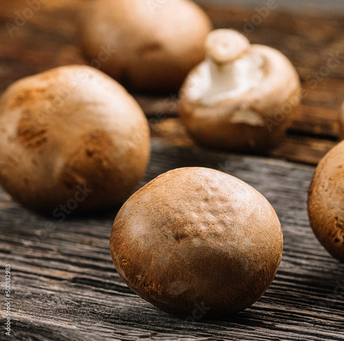 Several fresh champignons mushrooms on old wooden background, selective focus