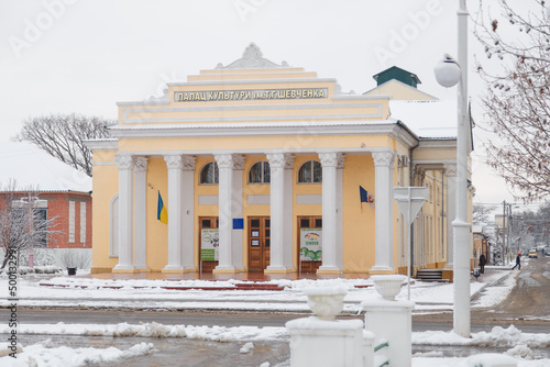 Palace of culture in name of Taras Shevchenko, famous Ukrainian poet and writer at winter day. Street covered with snow