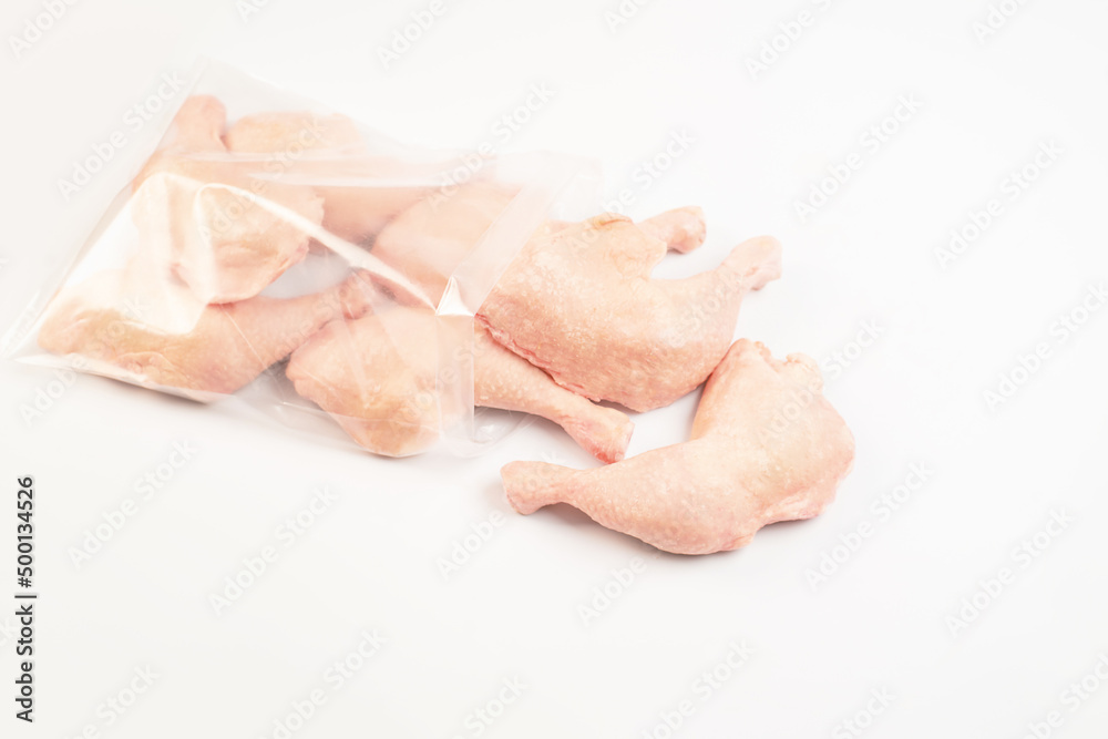 Chicken fresh meat in a transparent bag.Frozen pieces of chicken leg on an isolated white background.