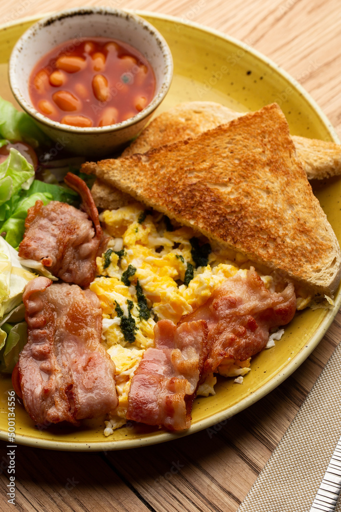 Poached eggs with vegetable, ham, tomatoes, red beans and sourdough toast isolated on wood background. Homemade food. Tasty breakfast. Poached eggs with vegetable, ham, tomatoes, red beans and sourdough toast isolated on wood background. Homemade food. Tasty breakfast.