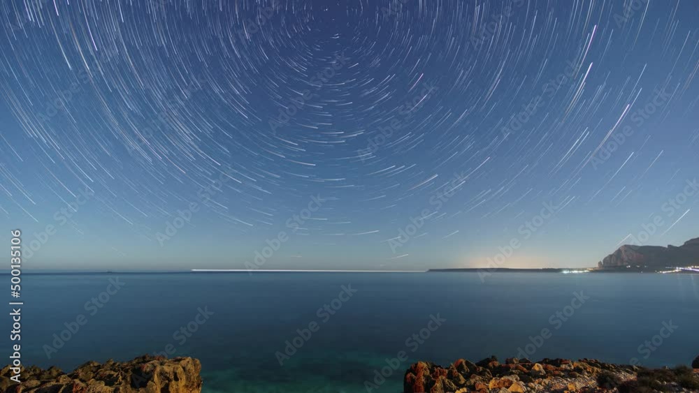 Startrails around polaris over rocky coastline of mediterranean sea with clear turquoise water at nature reserve of monte Cofano, Sicily