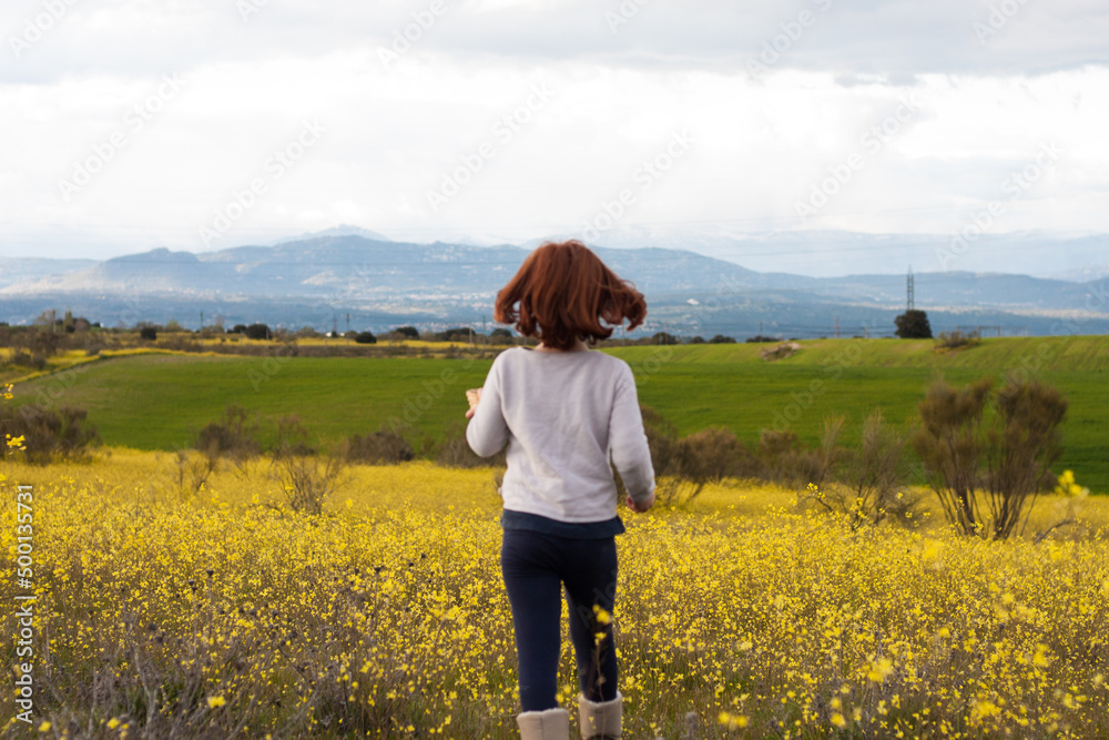 Chica jugando en el campo de flores amarillas